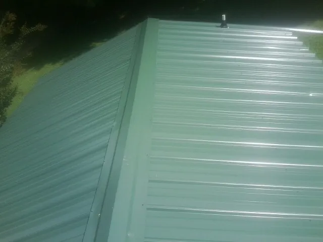 New green metal panels meeting at the ridge of a roof — Flat Roof Repair work by our crew in Riverview